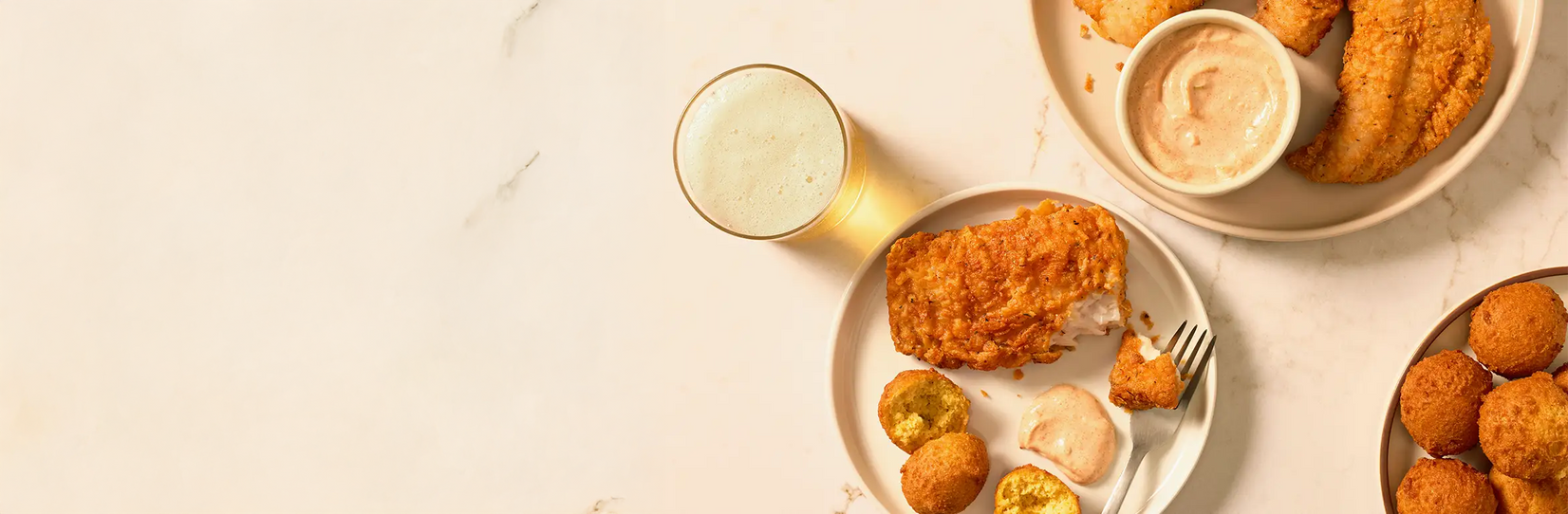 Assorted fried foods including chicken nuggets and waffle fries on a light background