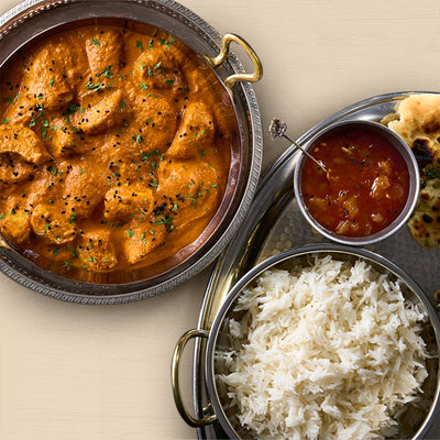 Dish of curry with rice and naan bread on a beige background