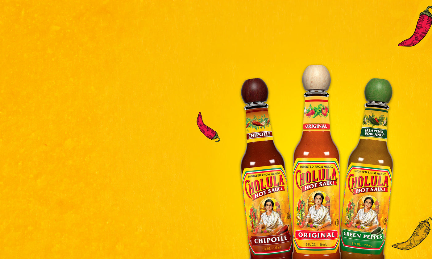 Three bottles of Cholula Chipotle, Original, and Green Pepper hot sauce on a yellow background.