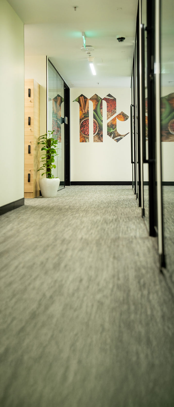 Office hallway with glass walls and a McCormick logo mural featuring spices.