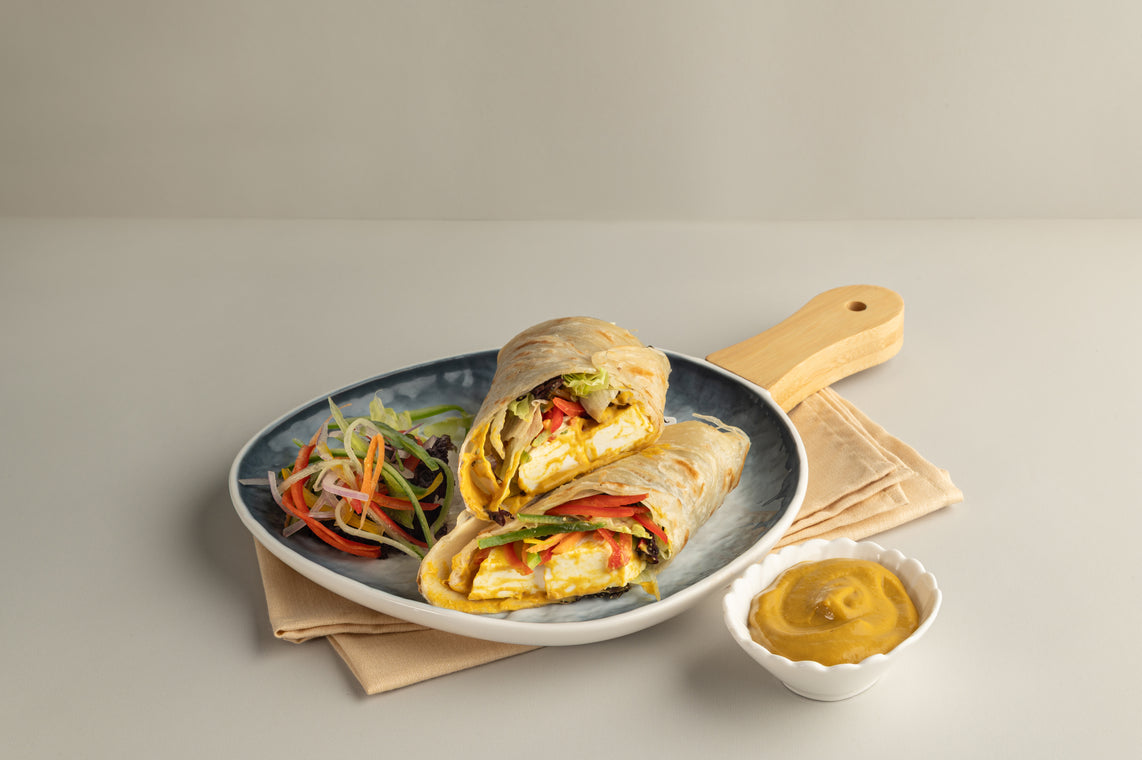 Vegetable wrap on a plate with salad and mustard on a neutral background